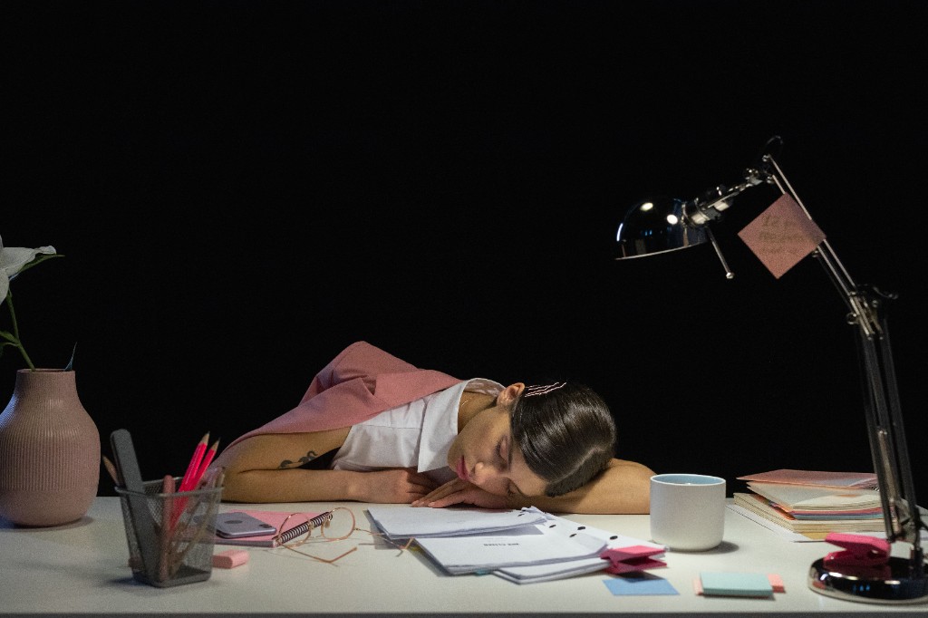 Tired person asleep at a desk after late work, showing stress and disrupted rest