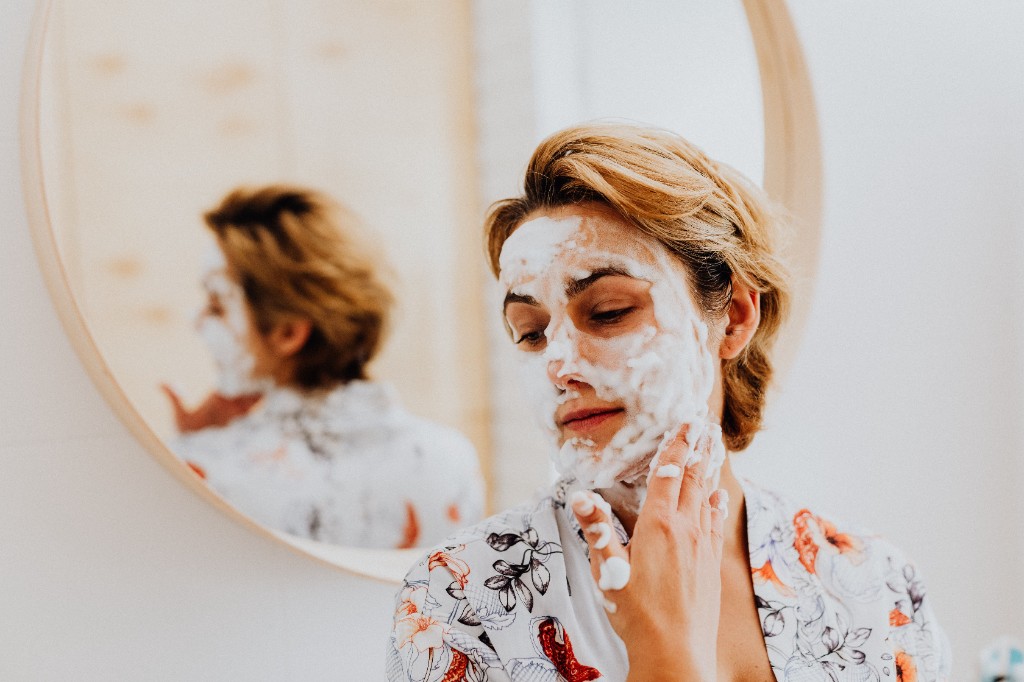 Woman applying a foamy facial cleanser as part of a daily skin routine